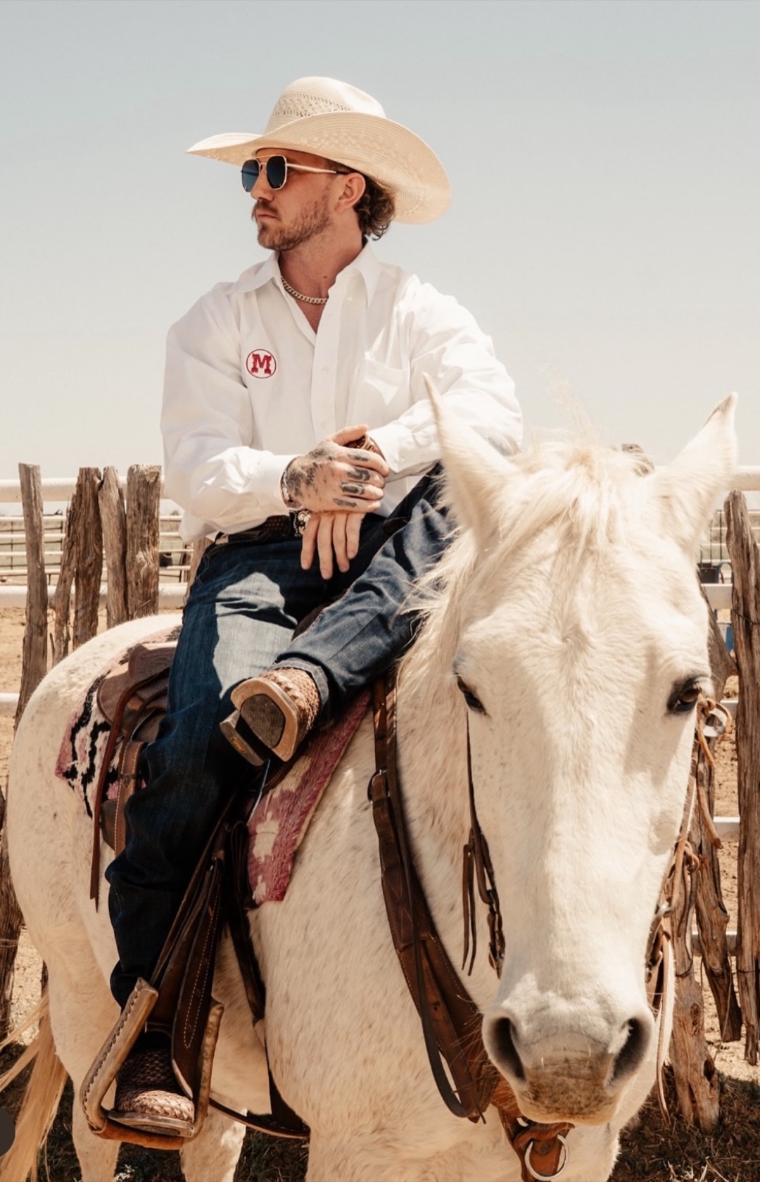 Trevor Brachtenbach wearing a cowboy hat, seated on a white horse